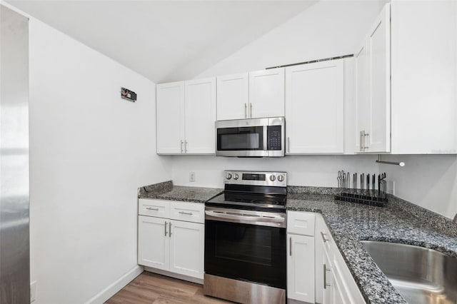 kitchen featuring a sink, stainless steel appliances, lofted ceiling, and white cabinets