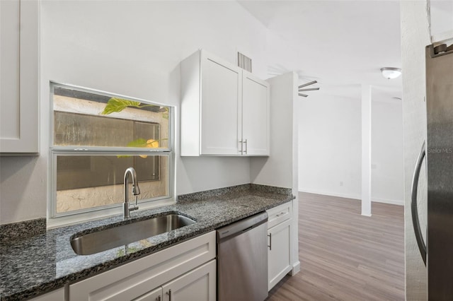 kitchen featuring visible vents, dark stone counters, appliances with stainless steel finishes, white cabinetry, and a sink