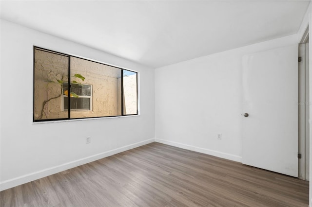 spare room featuring wood finished floors and baseboards