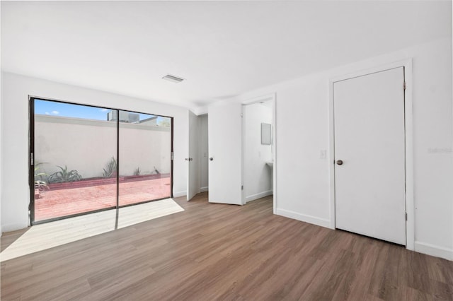 unfurnished bedroom featuring visible vents, baseboards, wood finished floors, and access to outside