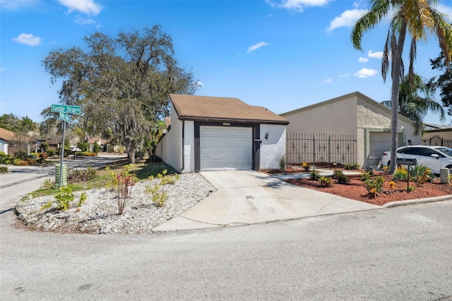 view of front of house featuring concrete driveway, fence, a garage, and stucco siding