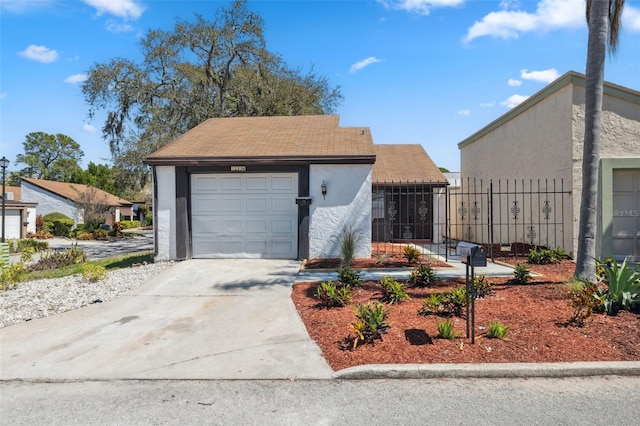 view of front of property with fence, a garage, driveway, and stucco siding