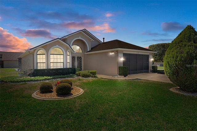 single story home with stucco siding, a front yard, a garage, and driveway