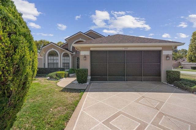 view of front of house with stucco siding, driveway, roof with shingles, a front yard, and a garage