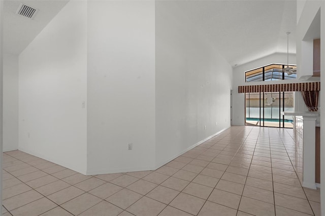 empty room featuring light tile patterned flooring, visible vents, and high vaulted ceiling