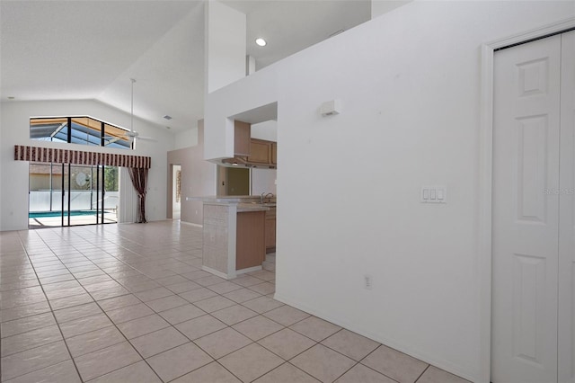 unfurnished living room featuring high vaulted ceiling, light tile patterned flooring, and a sink