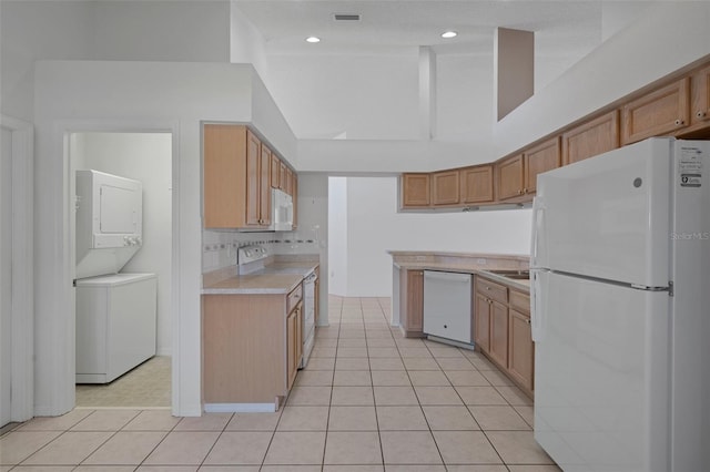 kitchen with white appliances, light tile patterned floors, visible vents, light countertops, and stacked washer / drying machine