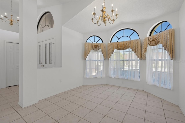 tiled spare room featuring a notable chandelier, a textured ceiling, and vaulted ceiling