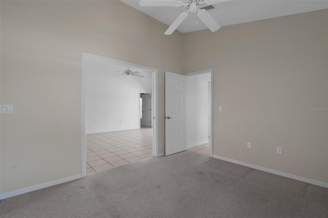 spare room with light carpet, baseboards, ceiling fan, and light tile patterned flooring