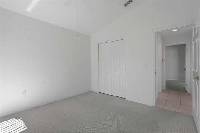 unfurnished bedroom with visible vents, a ceiling fan, a closet, lofted ceiling, and light colored carpet