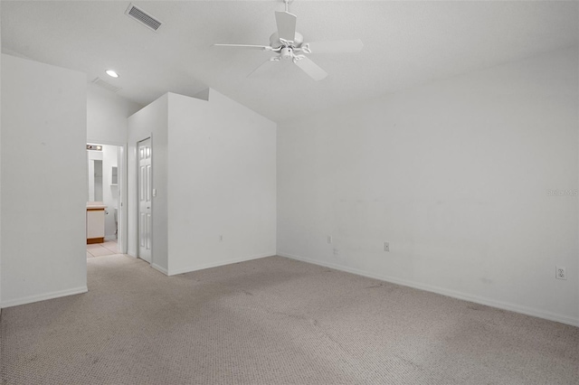 empty room featuring visible vents, baseboards, light colored carpet, vaulted ceiling, and a ceiling fan