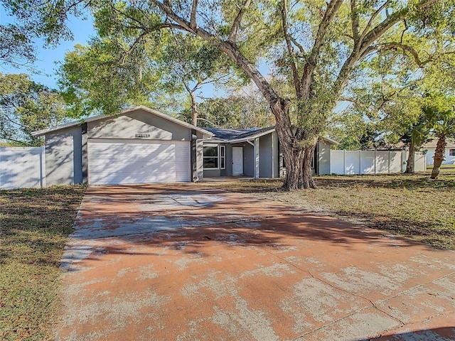 view of front of house with stucco siding, an attached garage, concrete driveway, and fence