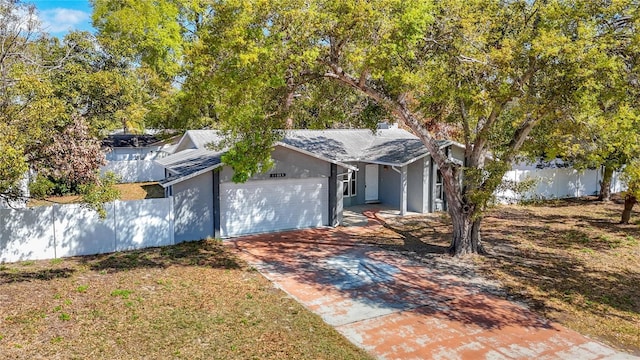 ranch-style home featuring a garage, concrete driveway, stucco siding, and fence