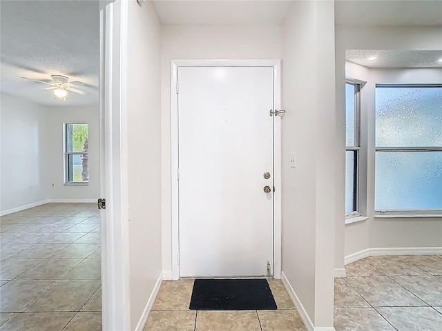 entrance foyer featuring light tile patterned flooring, a ceiling fan, and baseboards