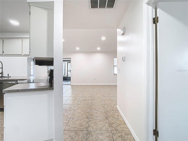 kitchen featuring visible vents, white cabinets, light tile patterned floors, dishwashing machine, and baseboards