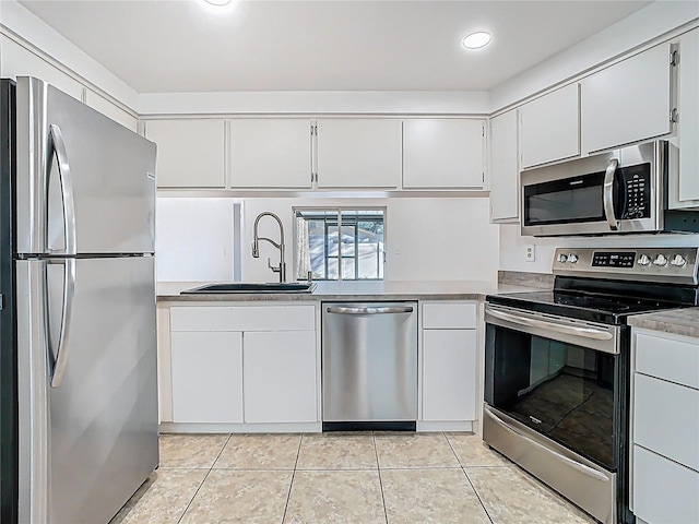 kitchen featuring light tile patterned floors, recessed lighting, appliances with stainless steel finishes, white cabinets, and a sink