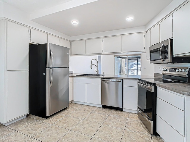 kitchen with a sink, dark countertops, white cabinetry, appliances with stainless steel finishes, and light tile patterned floors