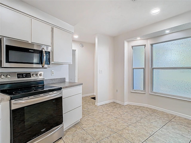 kitchen featuring white cabinetry, recessed lighting, appliances with stainless steel finishes, light tile patterned flooring, and baseboards