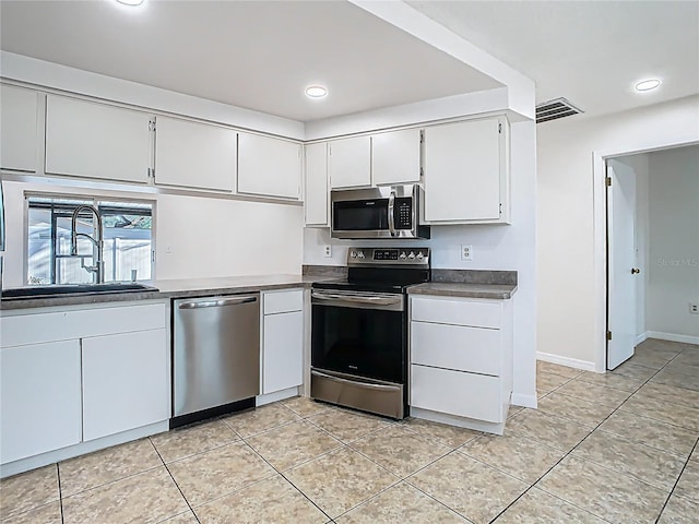 kitchen with dark countertops, light tile patterned floors, stainless steel appliances, and a sink