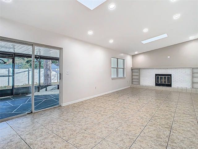 unfurnished living room with lofted ceiling with skylight, light tile patterned floors, a brick fireplace, and baseboards