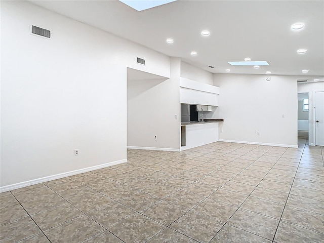 unfurnished living room with a skylight, light tile patterned floors, recessed lighting, and visible vents