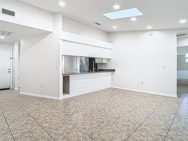 kitchen featuring visible vents, white cabinets, and a skylight