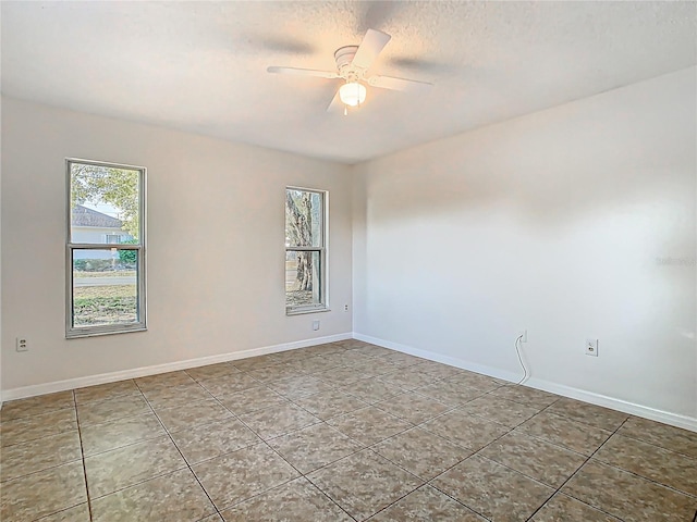 empty room featuring tile patterned floors, baseboards, a textured ceiling, and ceiling fan