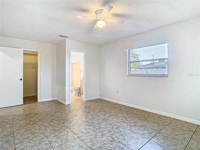 tiled empty room featuring visible vents, baseboards, a textured ceiling, and ceiling fan