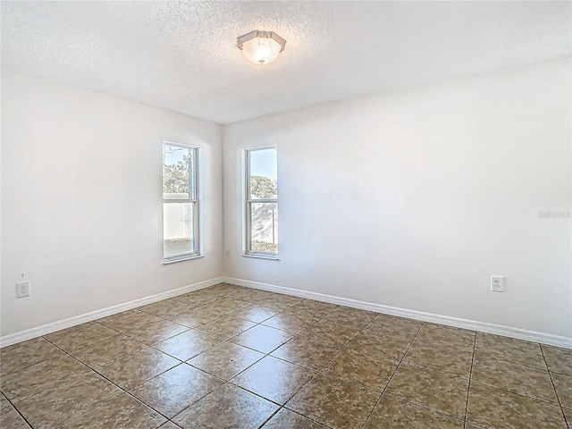 unfurnished room with tile patterned flooring, a textured ceiling, and baseboards