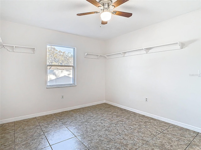 empty room with tile patterned flooring, baseboards, and ceiling fan