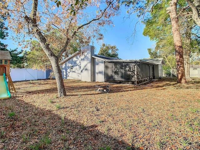 back of house with a playground and fence