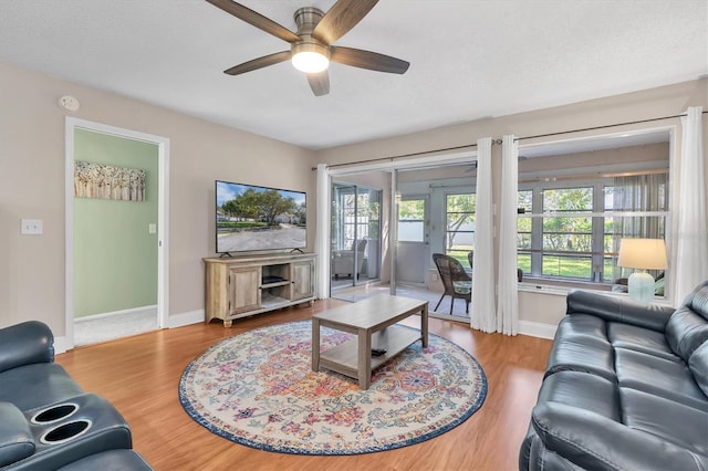 living room with baseboards, wood finished floors, a textured ceiling, and ceiling fan