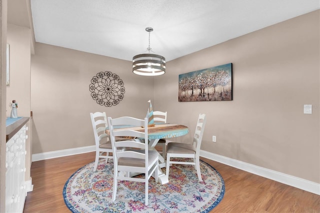 dining area featuring a chandelier, baseboards, and wood finished floors