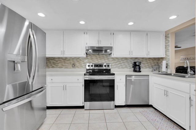 kitchen with tasteful backsplash, under cabinet range hood, light countertops, light tile patterned floors, and appliances with stainless steel finishes