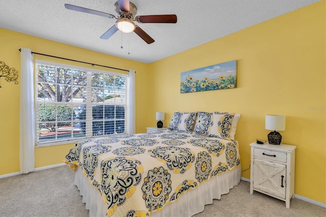 bedroom featuring baseboards, light carpet, a textured ceiling, and a ceiling fan