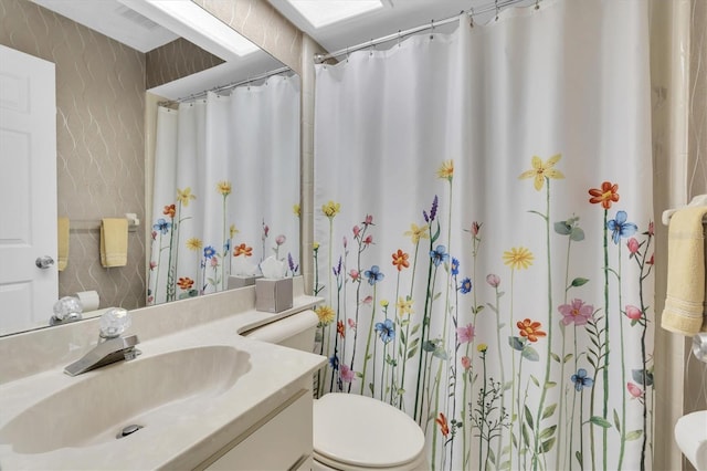 bathroom featuring toilet, vanity, and a shower with curtain