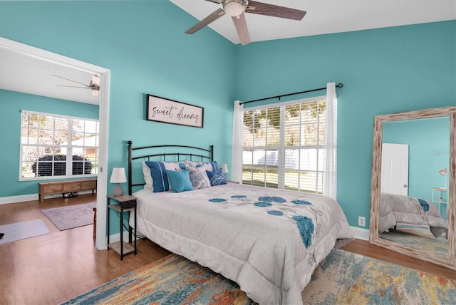 bedroom with baseboards, lofted ceiling, wood finished floors, and a ceiling fan