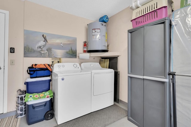 washroom featuring water heater, laundry area, washer and dryer, and a textured ceiling