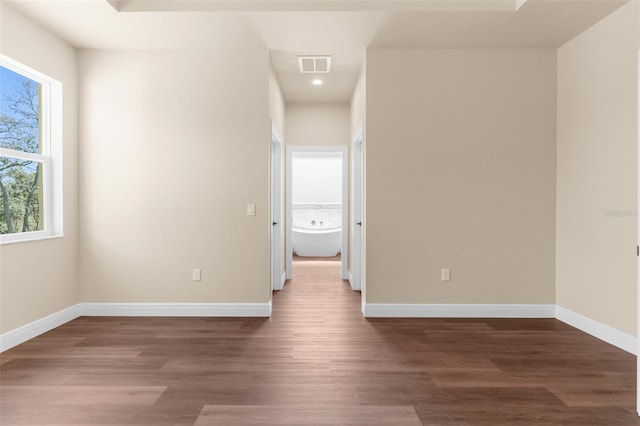 unfurnished room with wood finished floors, visible vents, and baseboards