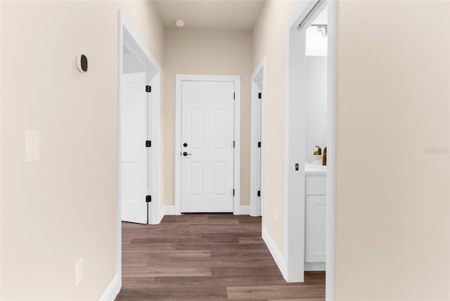 corridor featuring baseboards and wood finished floors