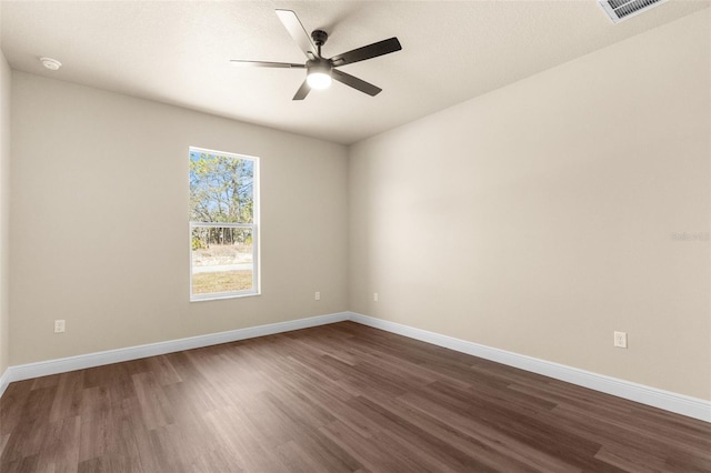 empty room featuring ceiling fan, visible vents, baseboards, and dark wood-style floors