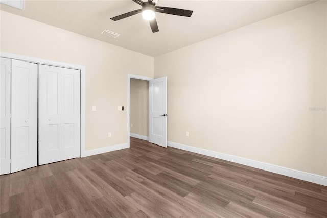 unfurnished bedroom with a closet, baseboards, visible vents, and wood finished floors