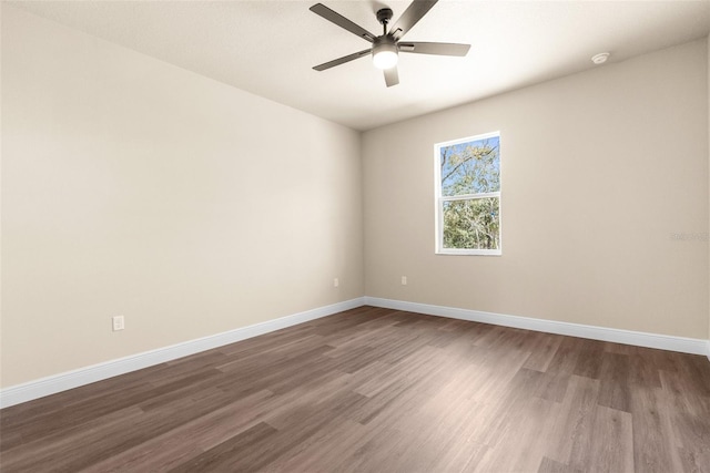 empty room featuring baseboards, dark wood finished floors, and a ceiling fan