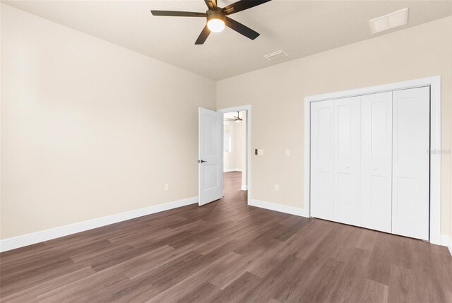 unfurnished bedroom with a ceiling fan, baseboards, visible vents, dark wood-style flooring, and a closet