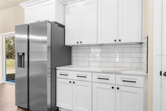 kitchen with white cabinetry, stainless steel fridge, and backsplash