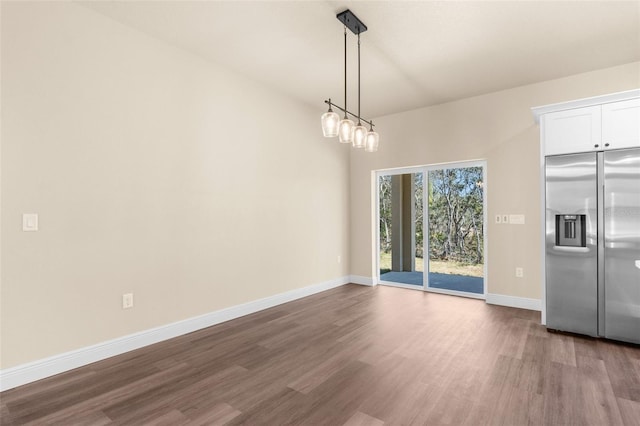 unfurnished dining area featuring dark wood finished floors and baseboards