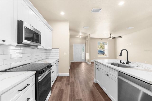 kitchen featuring a sink, backsplash, appliances with stainless steel finishes, white cabinetry, and dark wood-style flooring