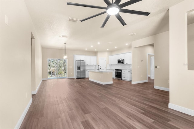 unfurnished living room with ceiling fan, visible vents, dark wood-style flooring, and a sink