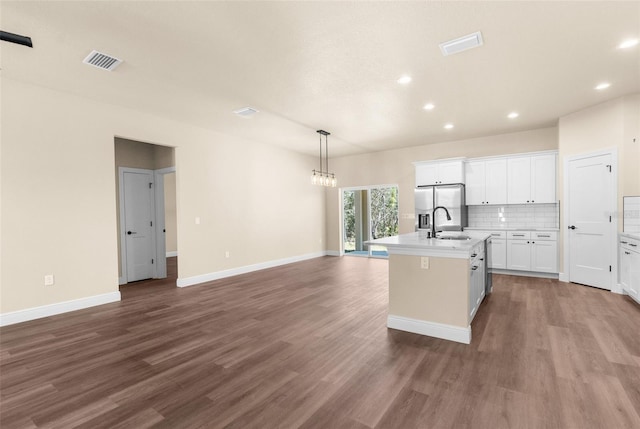 kitchen with visible vents, stainless steel fridge with ice dispenser, decorative backsplash, wood finished floors, and a sink