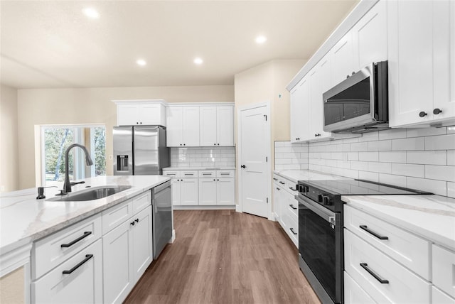 kitchen with a sink, stainless steel appliances, light wood-style floors, white cabinetry, and tasteful backsplash